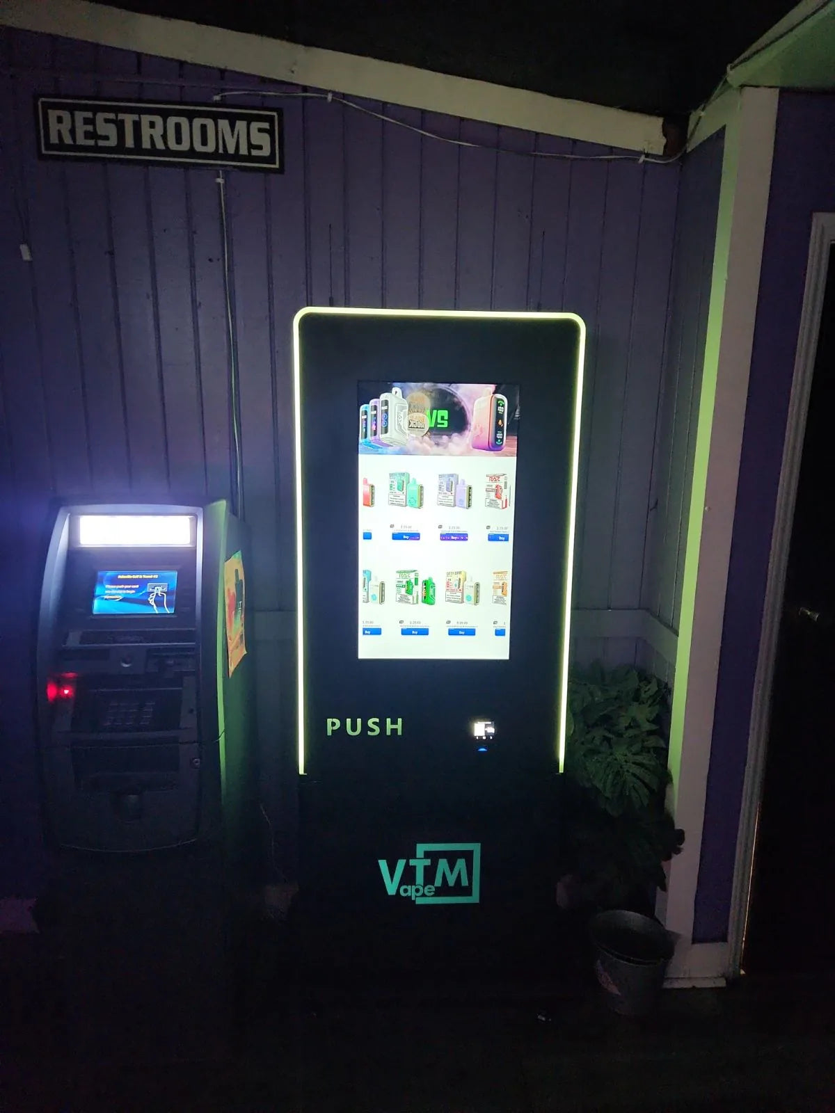 VTM vape vending machine installed beside an ATM near the restrooms in a dimly lit bar